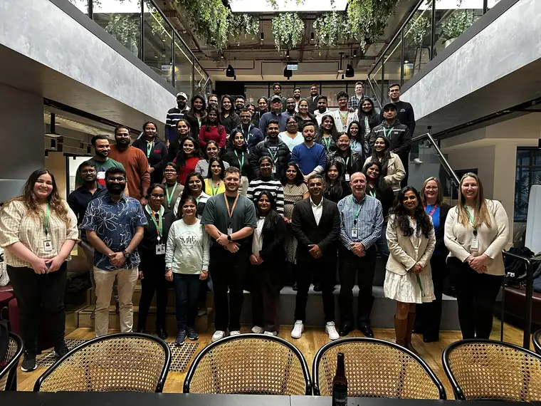 A large team gathered on an indoor staircase for a group photo