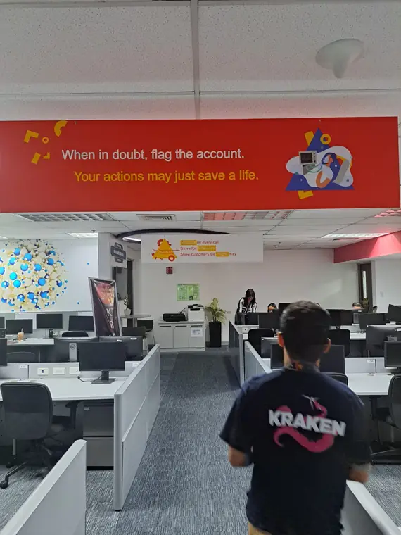 A contact centre floor, with a colleague in a Kraken T-shirt walking between rows of desks