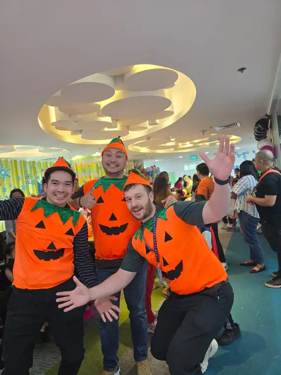 Three colleagues in pumpkin costumes at an office Halloween celebration